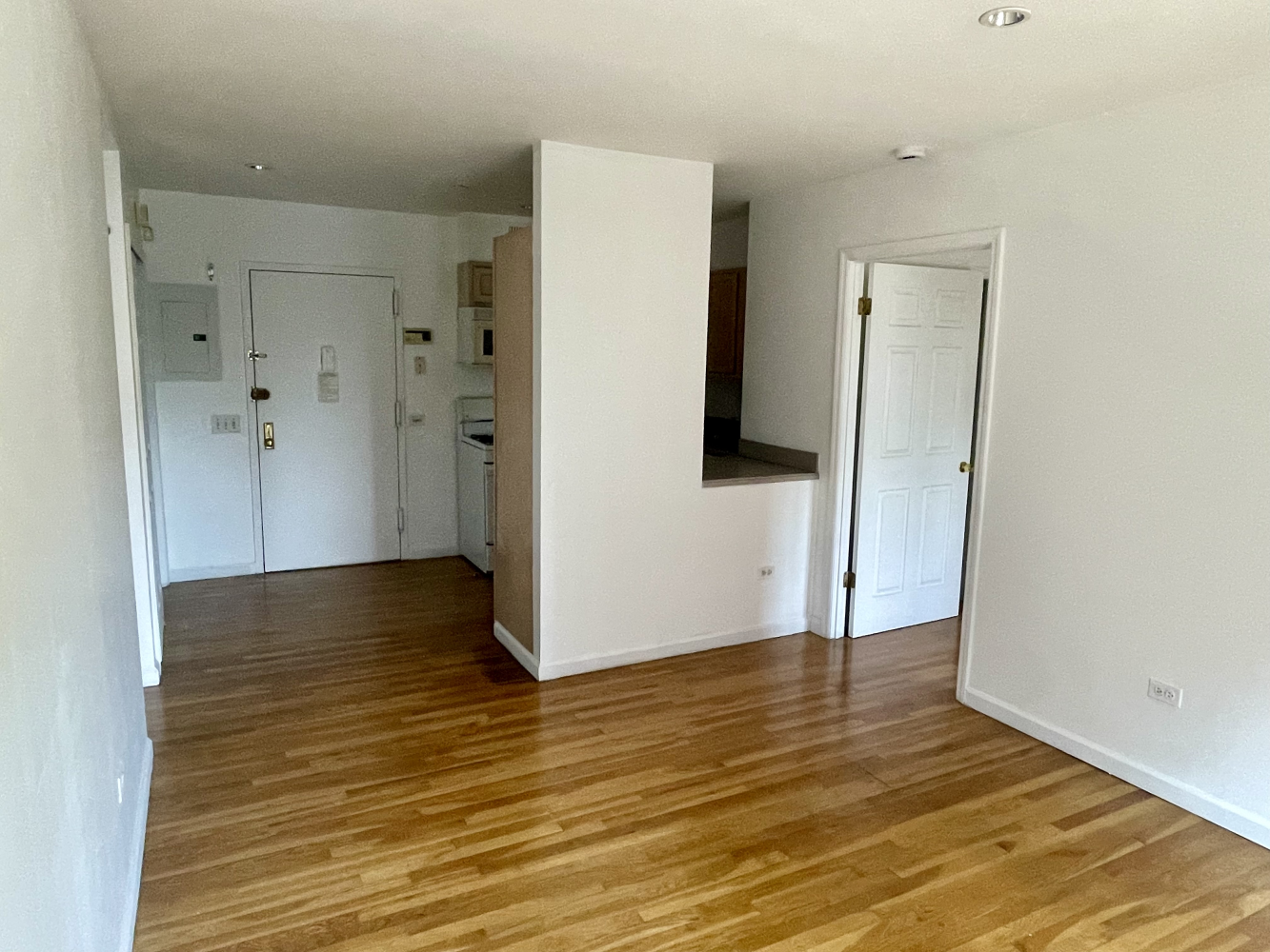 a view of an empty room with wooden floor and closet