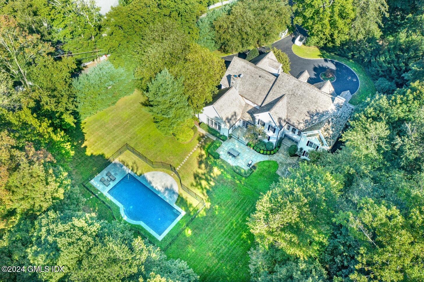 an aerial view of residential house with outdoor space and trees all around