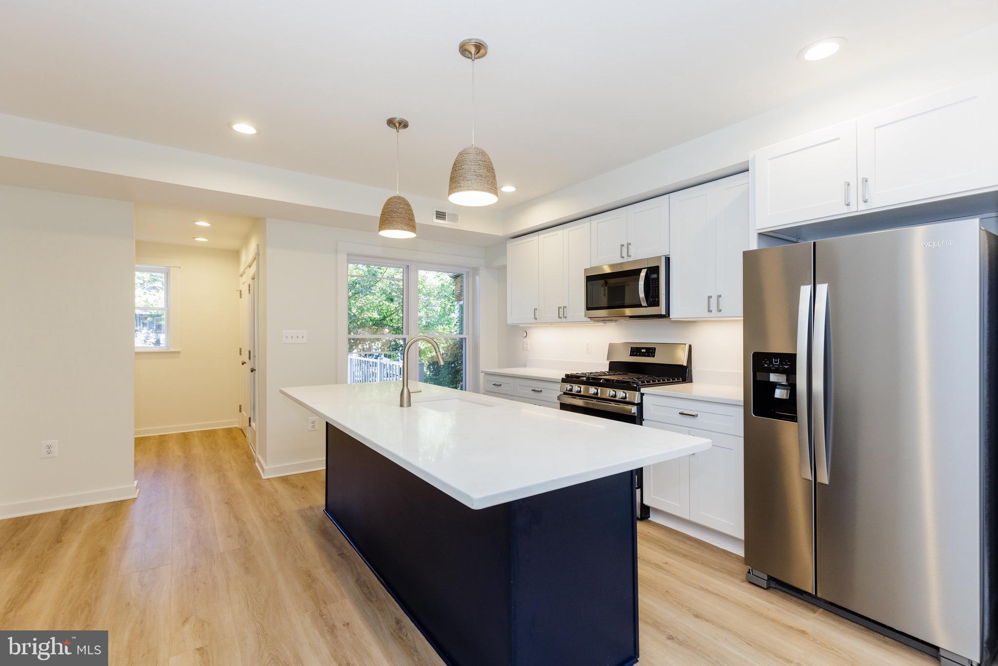 a large kitchen with a center island wooden floor stainless steel appliances and windows