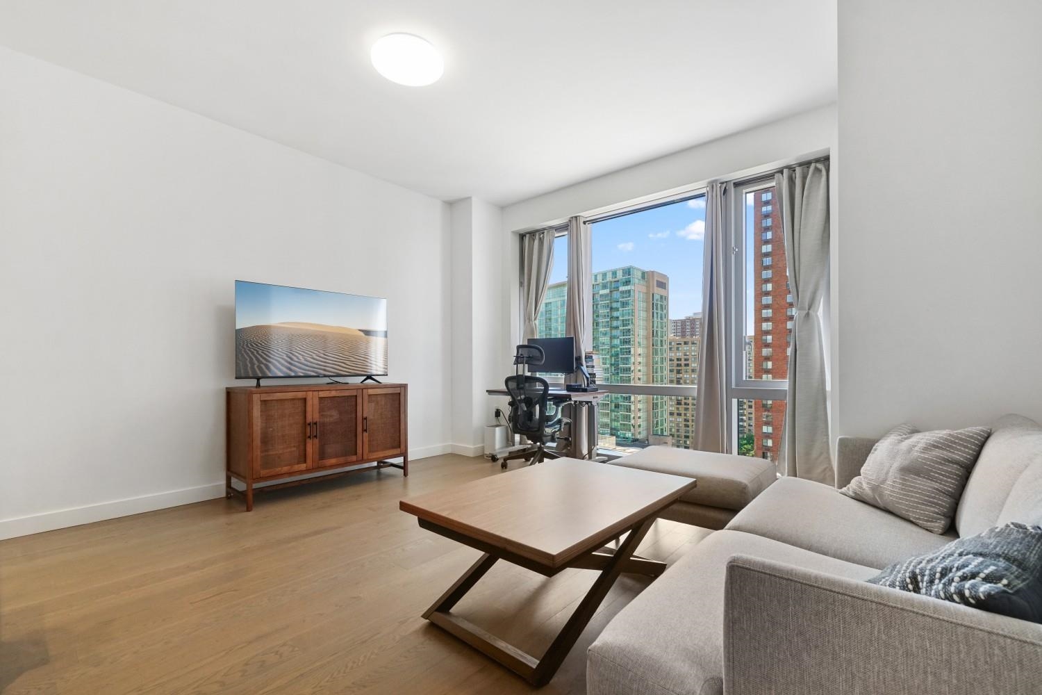 a living room with furniture a window and a flat screen tv