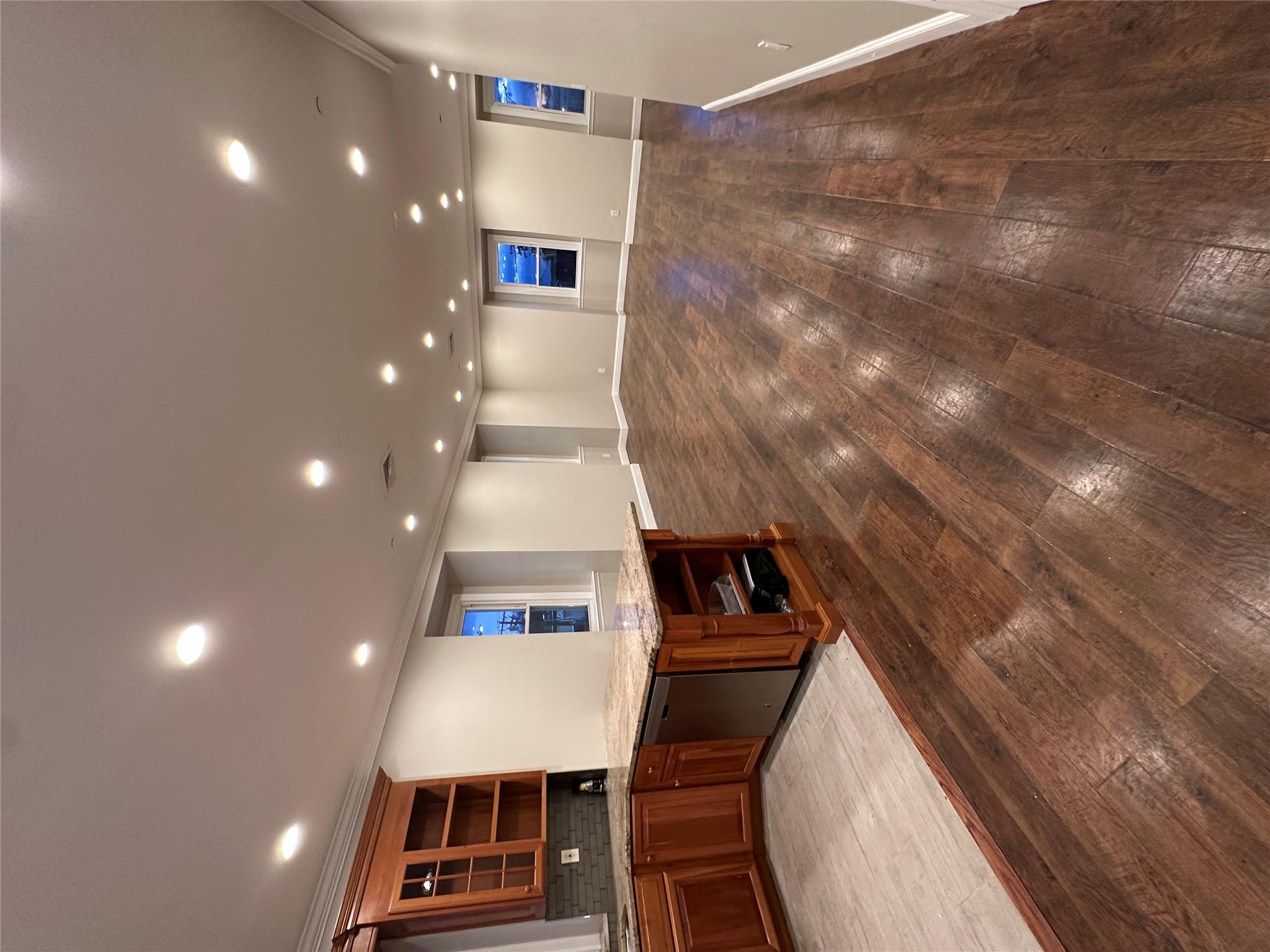 Bar featuring dishwashing machine, hardwood / wood-style floors, light stone counters, and ornamental molding