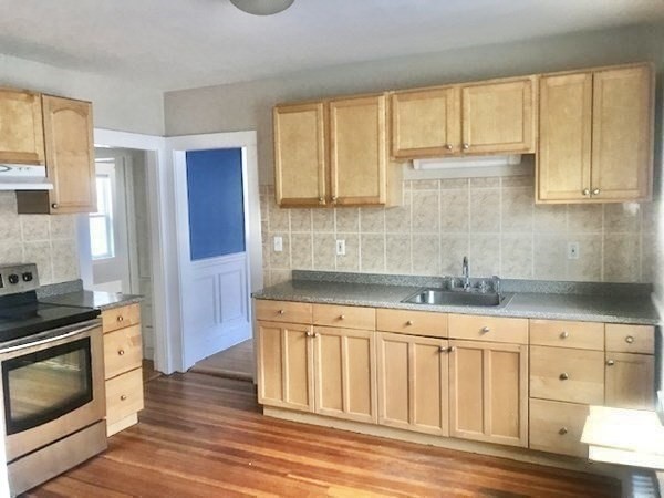 a kitchen with granite countertop a sink cabinets stainless steel appliances and a window