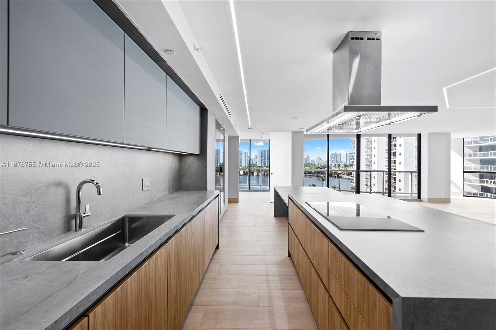 a large white kitchen with kitchen island a large counter space a sink a window and stainless steel appliances