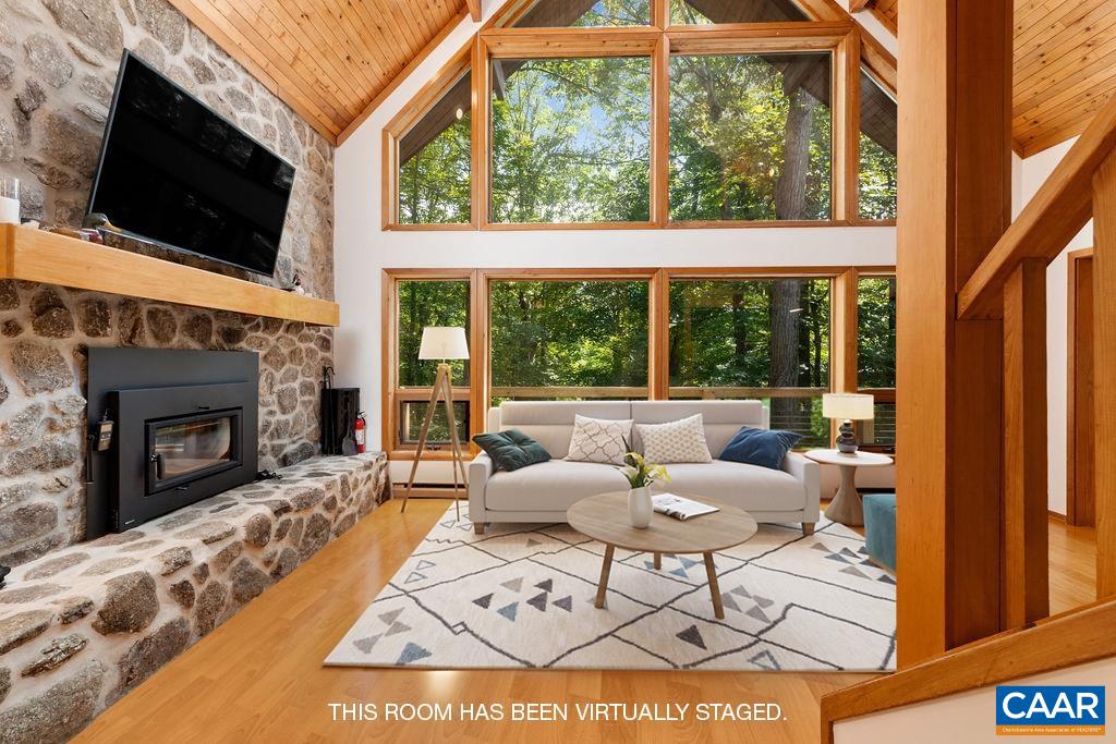 a living room with a fireplace a flat screen tv and a floor to ceiling window