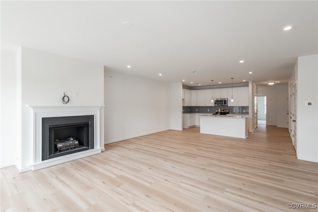 a view of kitchen and empty room with wooden floor