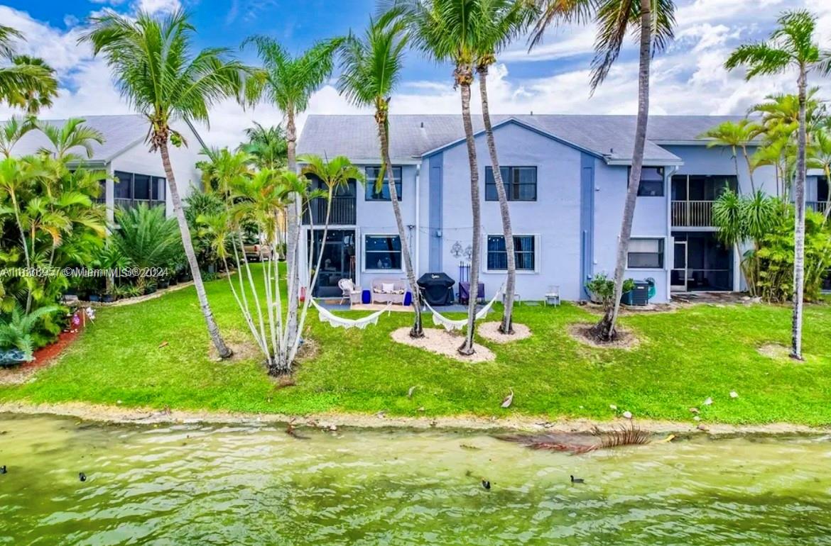 front view of a house with a yard and palm trees