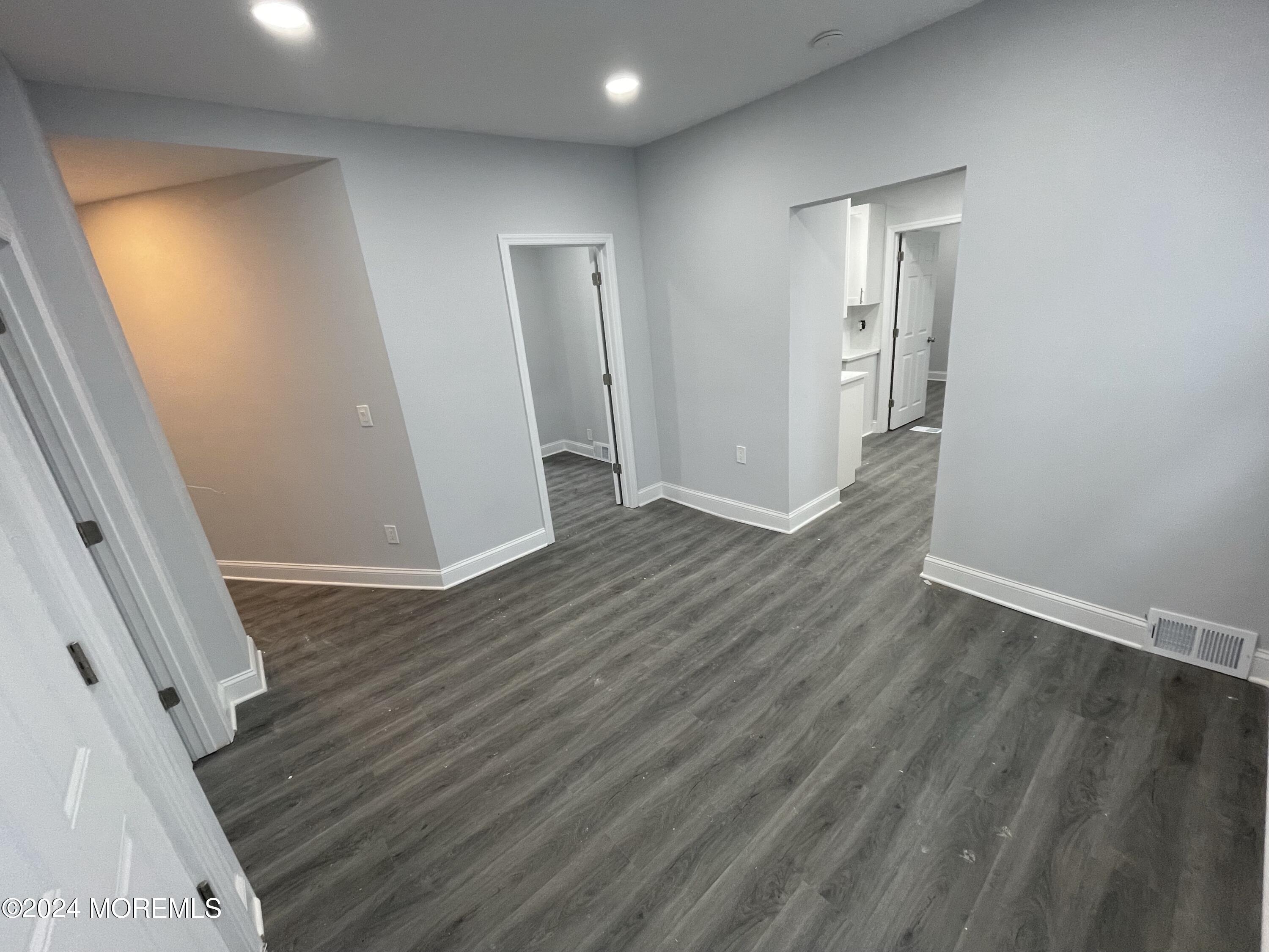 an empty room with wooden floor and entrance