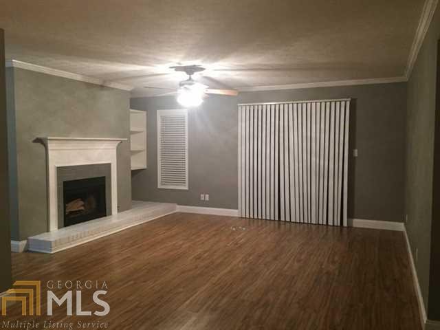 an empty room with wooden floor fireplace and windows