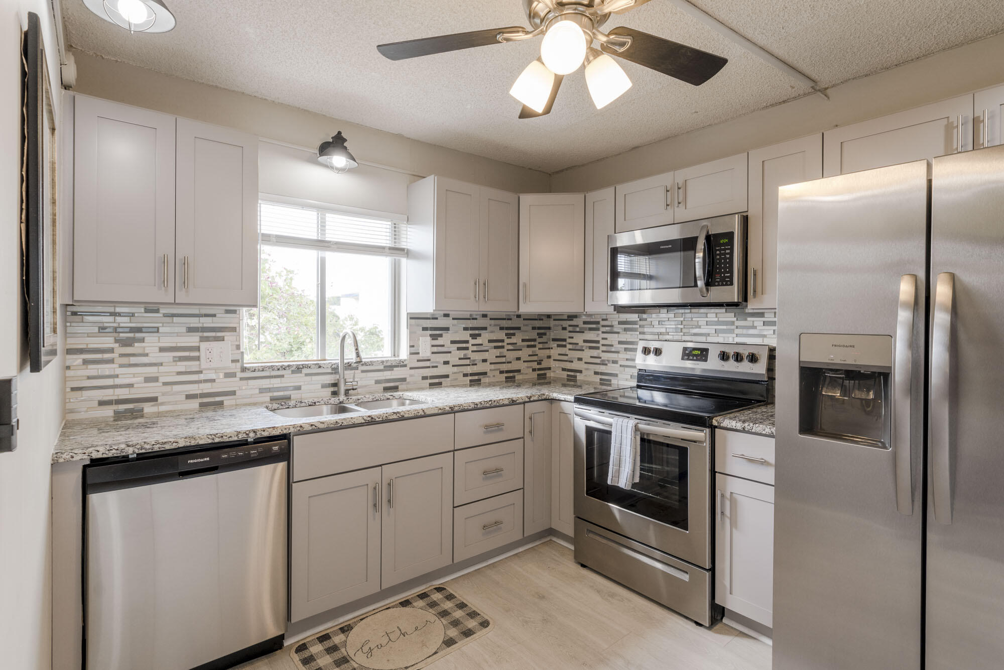 a kitchen with stainless steel appliances granite countertop a stove sink microwave refrigerator and cabinets