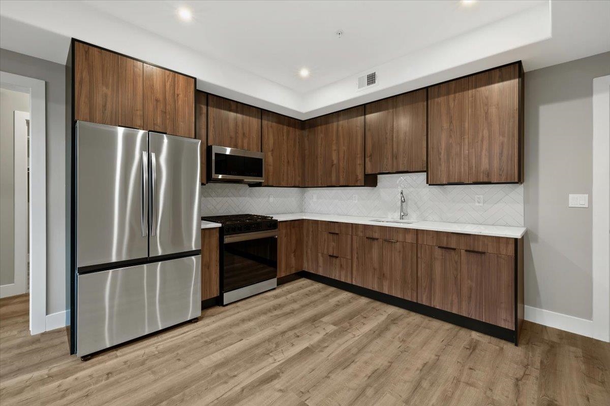 a kitchen with granite countertop wooden cabinets a refrigerator and a sink