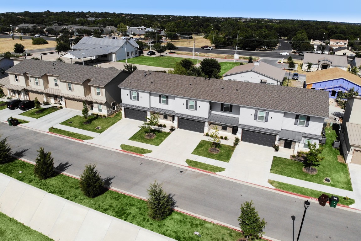 an aerial view of residential houses with outdoor space and parking