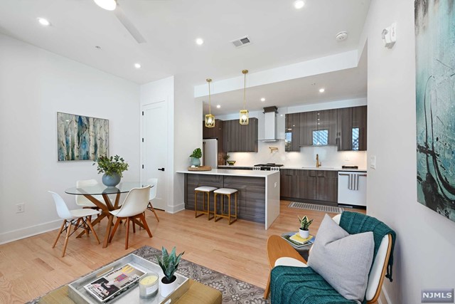 a living room with furniture kitchen view and a wooden floor