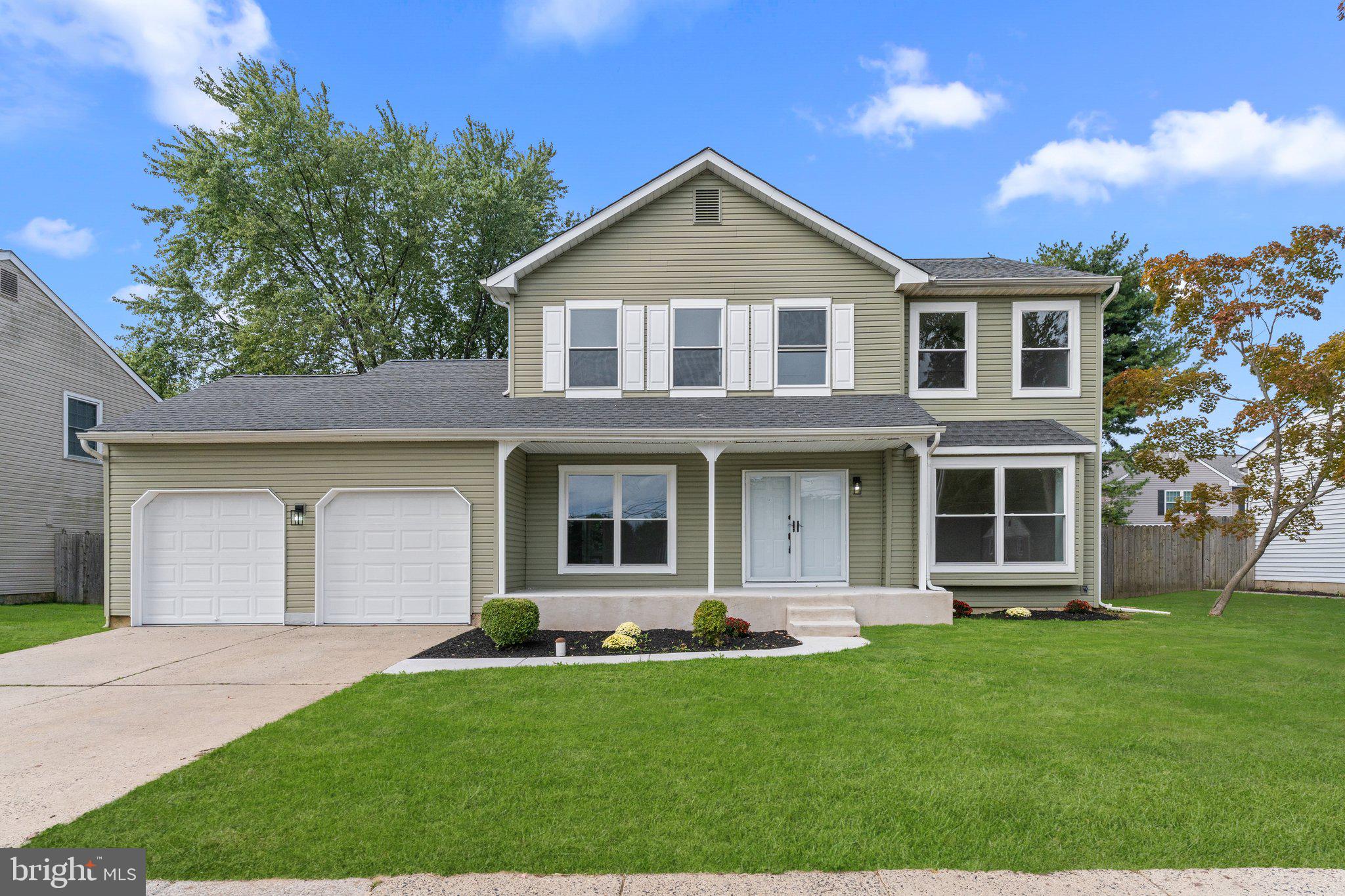 a front view of a house with a yard and trees