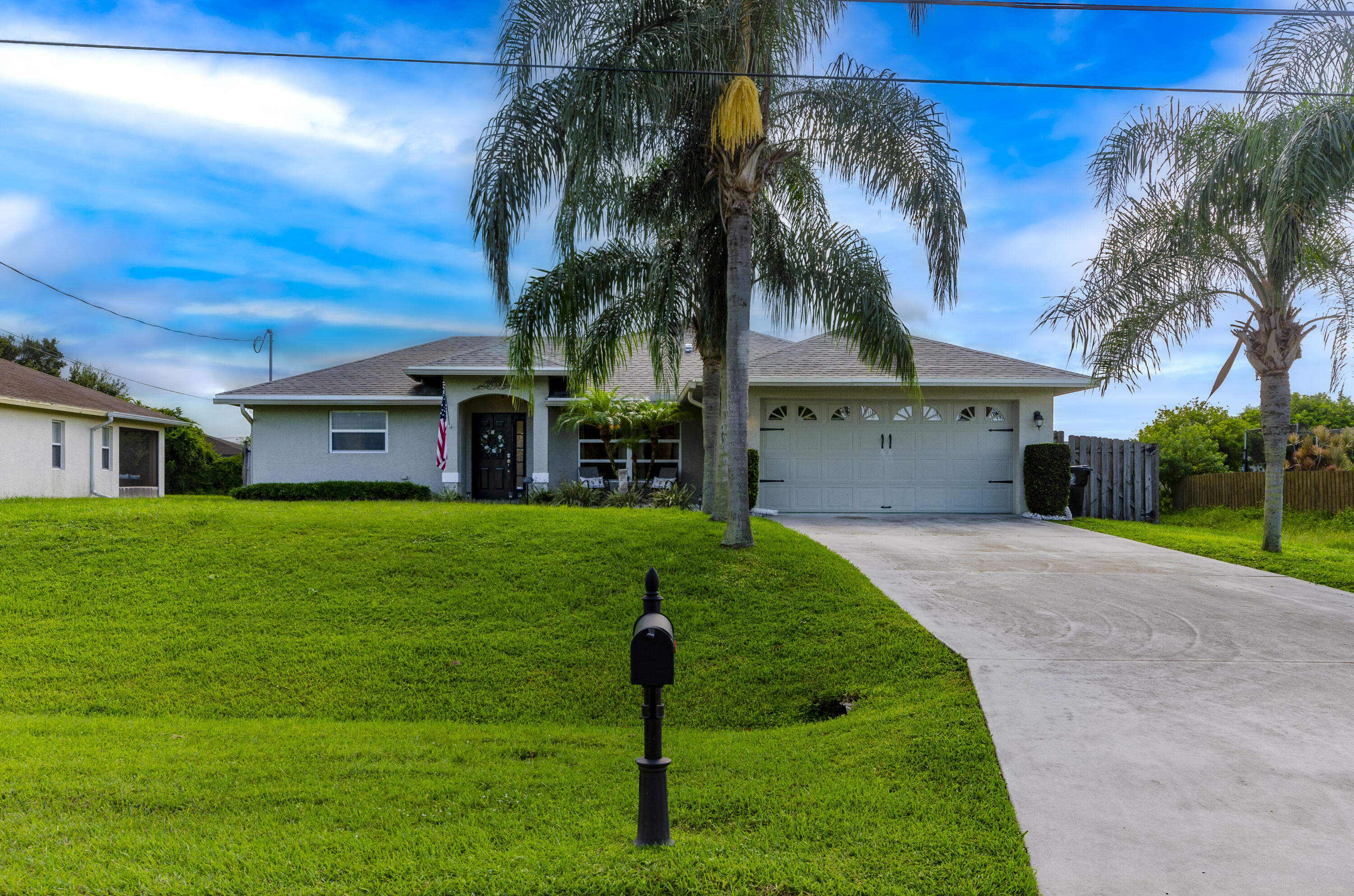 a front view of a house with a yard and palm trees