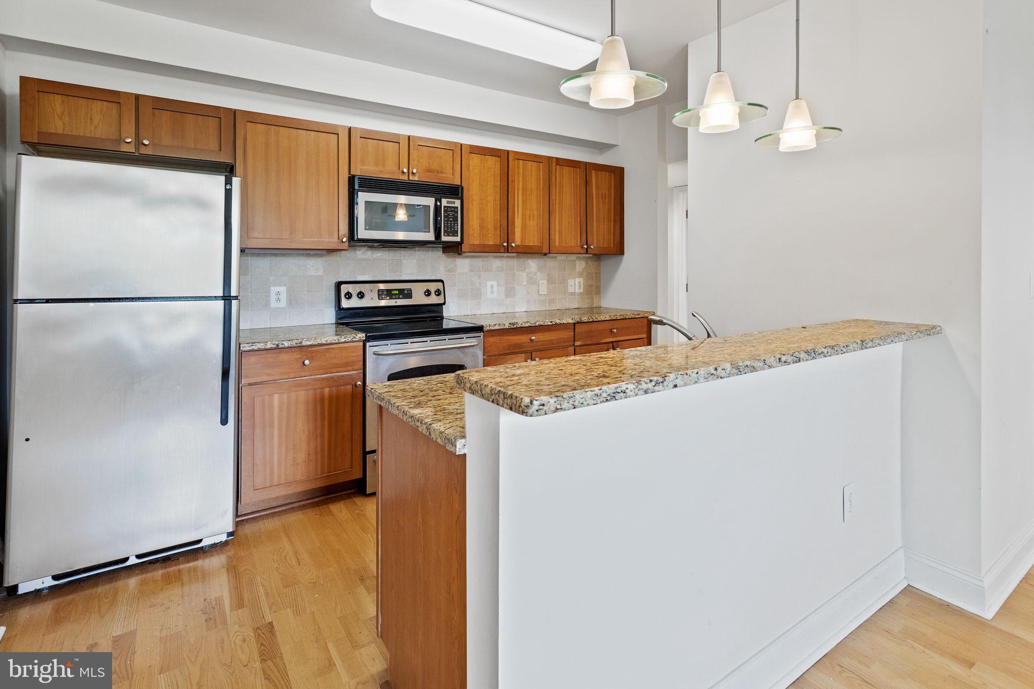 a kitchen with granite countertop cabinets stainless steel appliances and a counter space