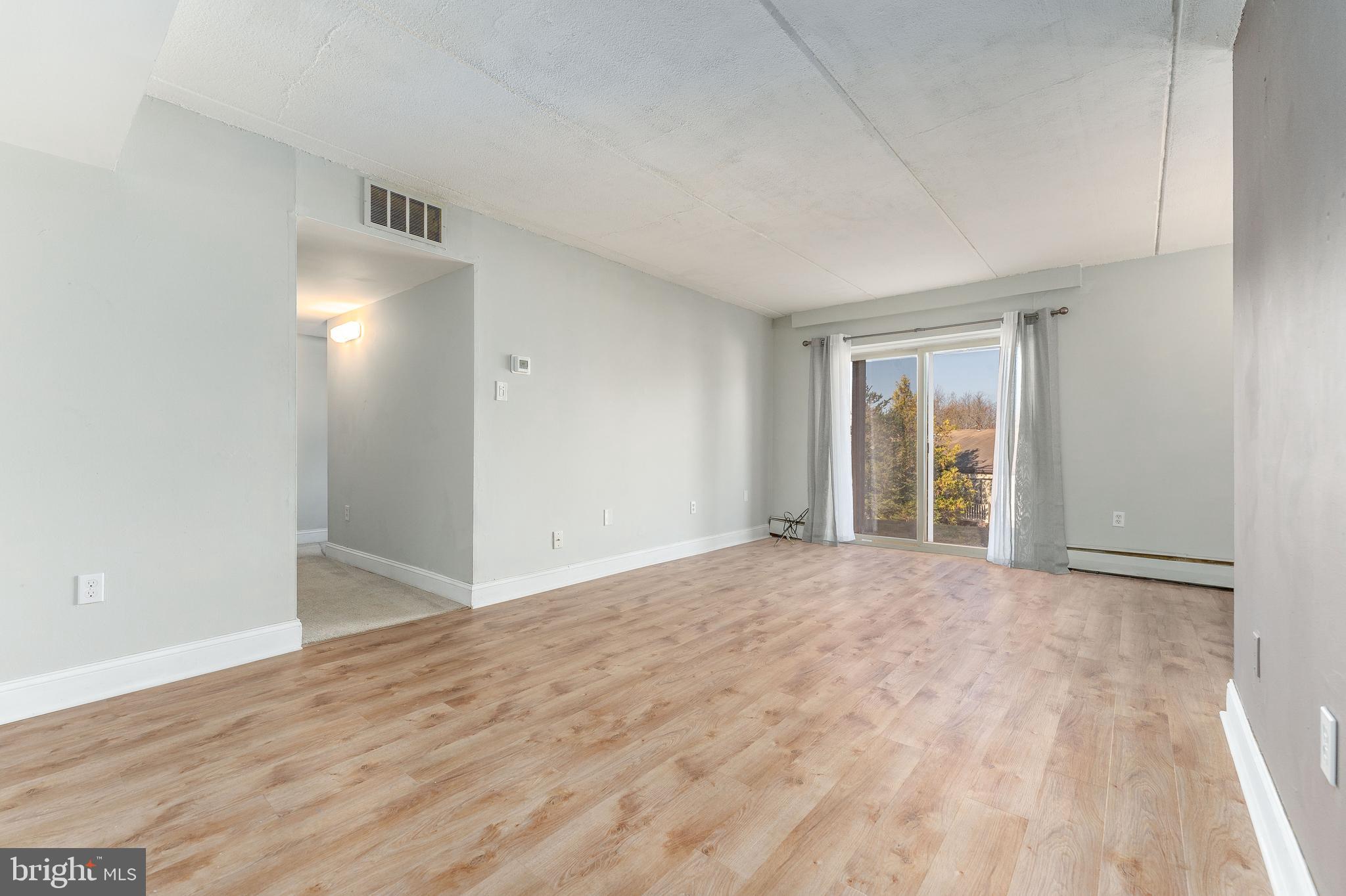 a view of an empty room with wooden floor and a window