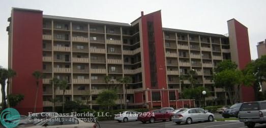 a front view of a building with cars parked