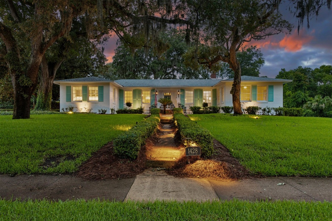 a front view of a house with a garden and trees