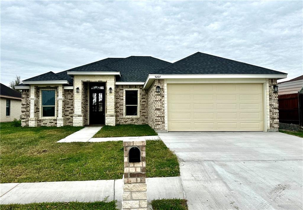 View of front of home with a garage and a front lawn