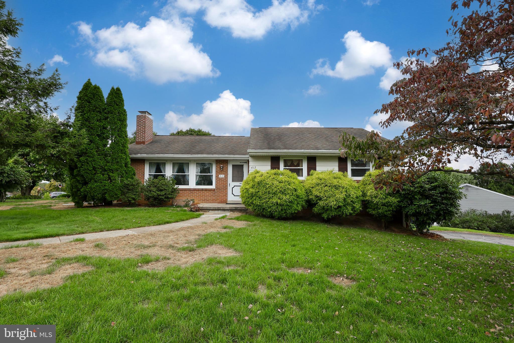 a view of a house next to a big yard and large trees