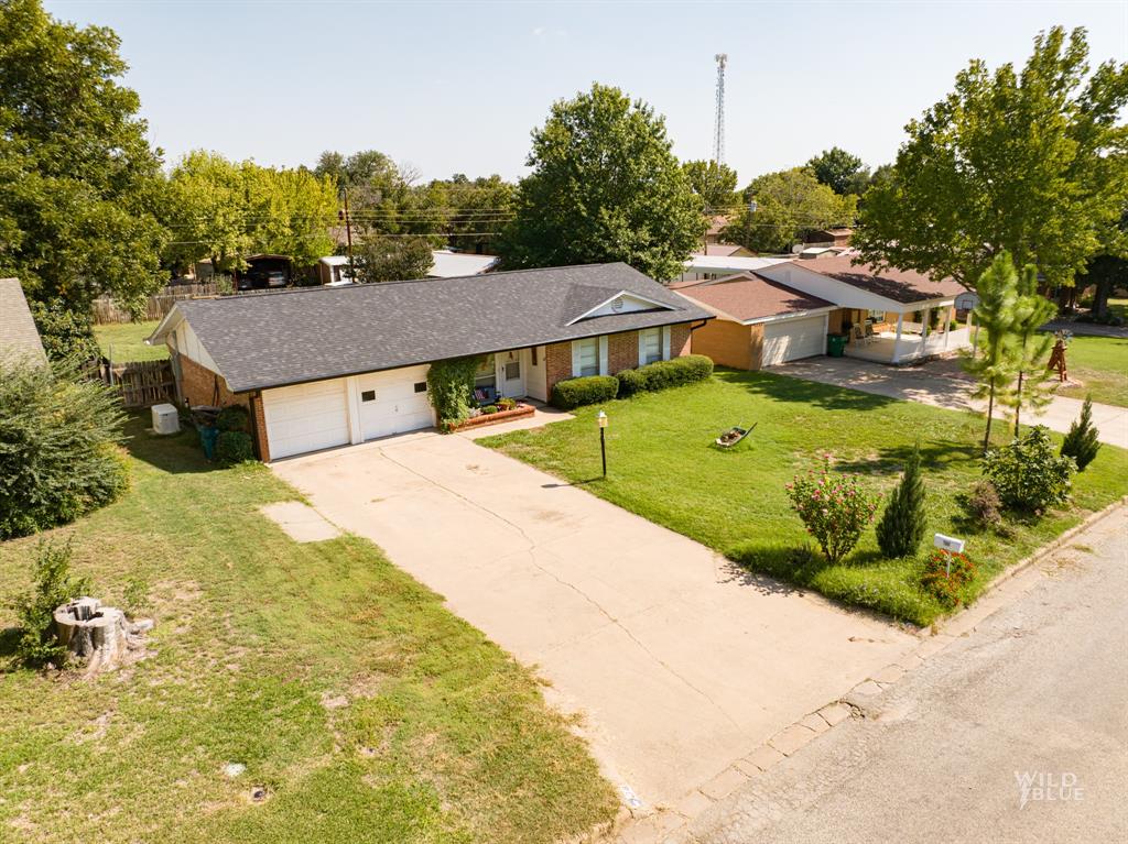 a view of a house with a big yard plants and large tree