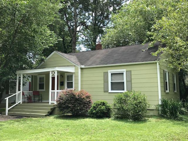 a view of a house with a yard plants and large tree