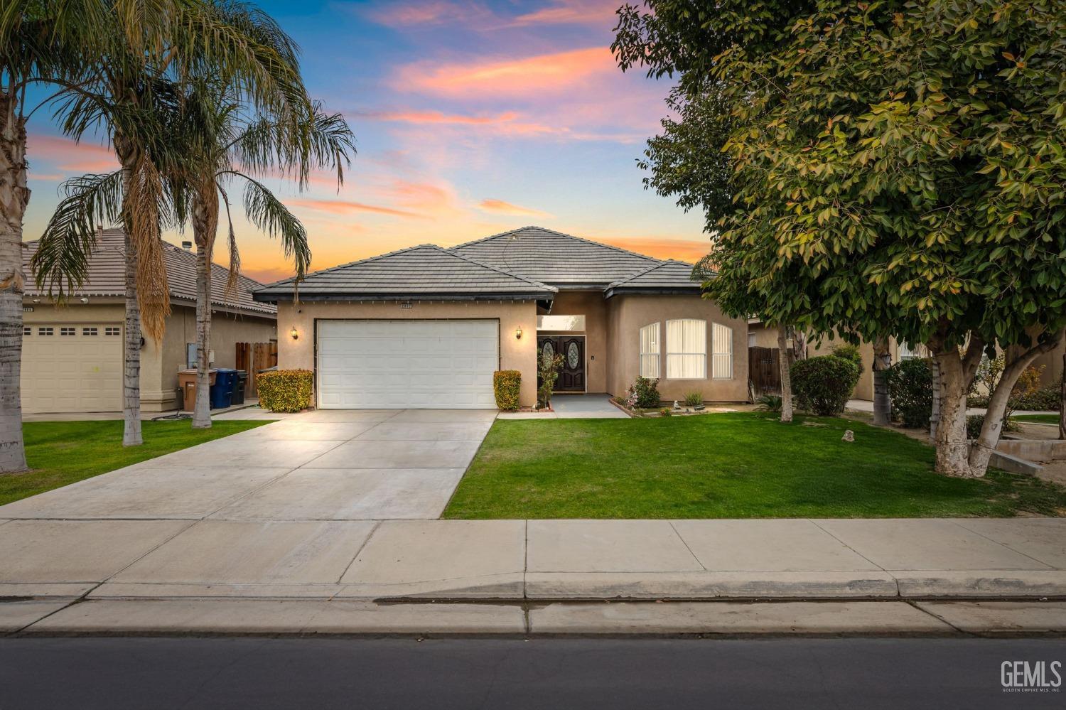 a view of a house with a yard and palm trees