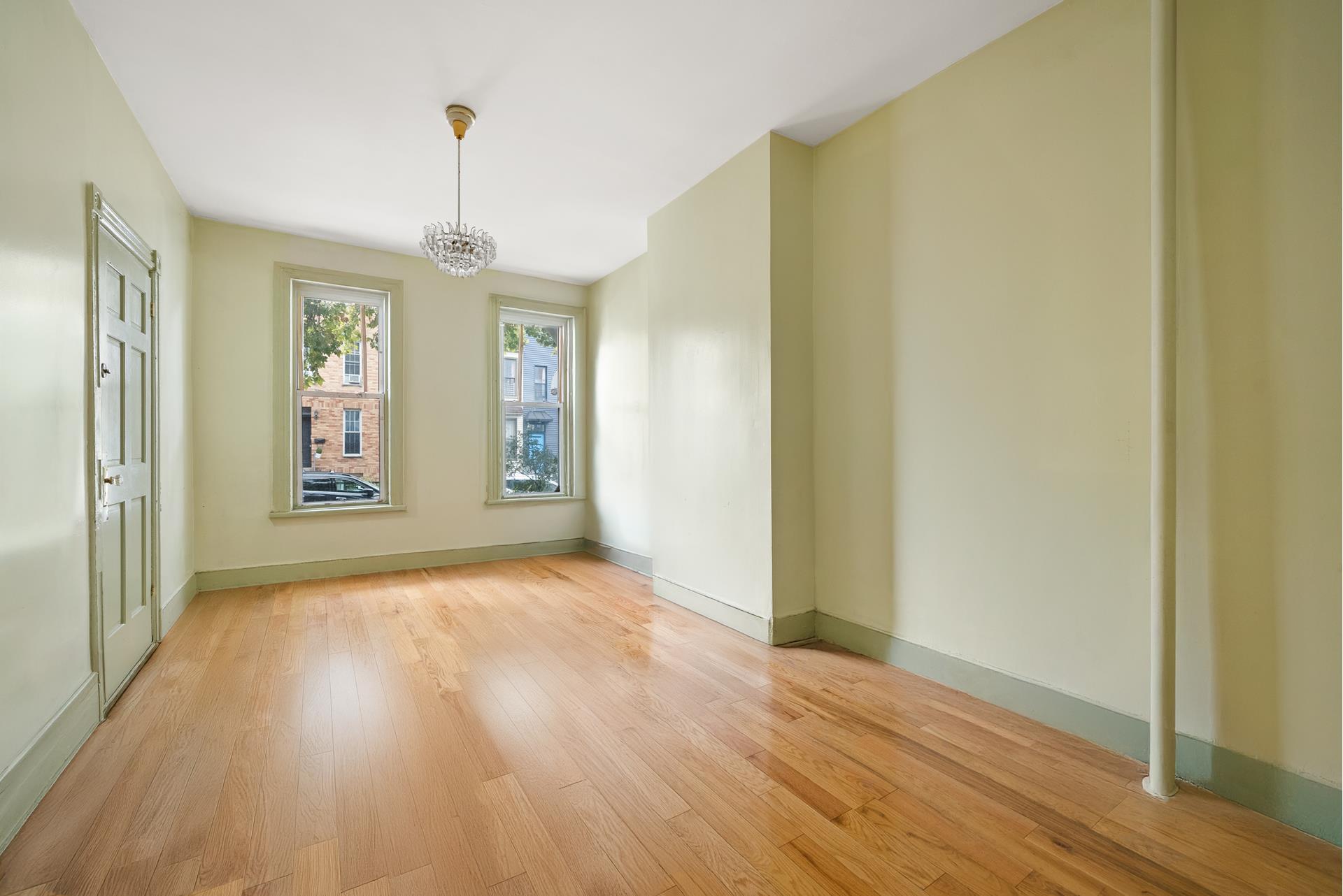 a view of an empty room with window and wooden floor