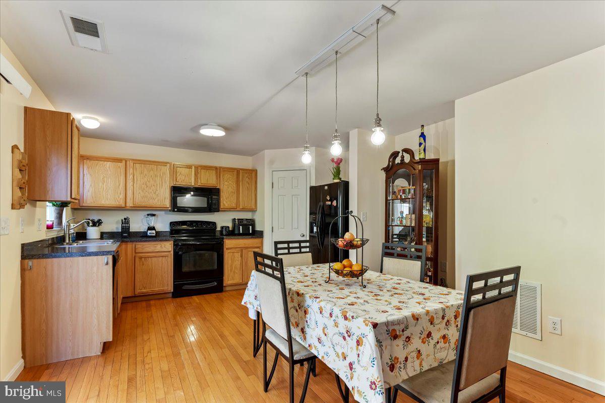 a kitchen with stainless steel appliances kitchen island granite countertop a stove a refrigerator a sink a dining table and chairs with wooden floor