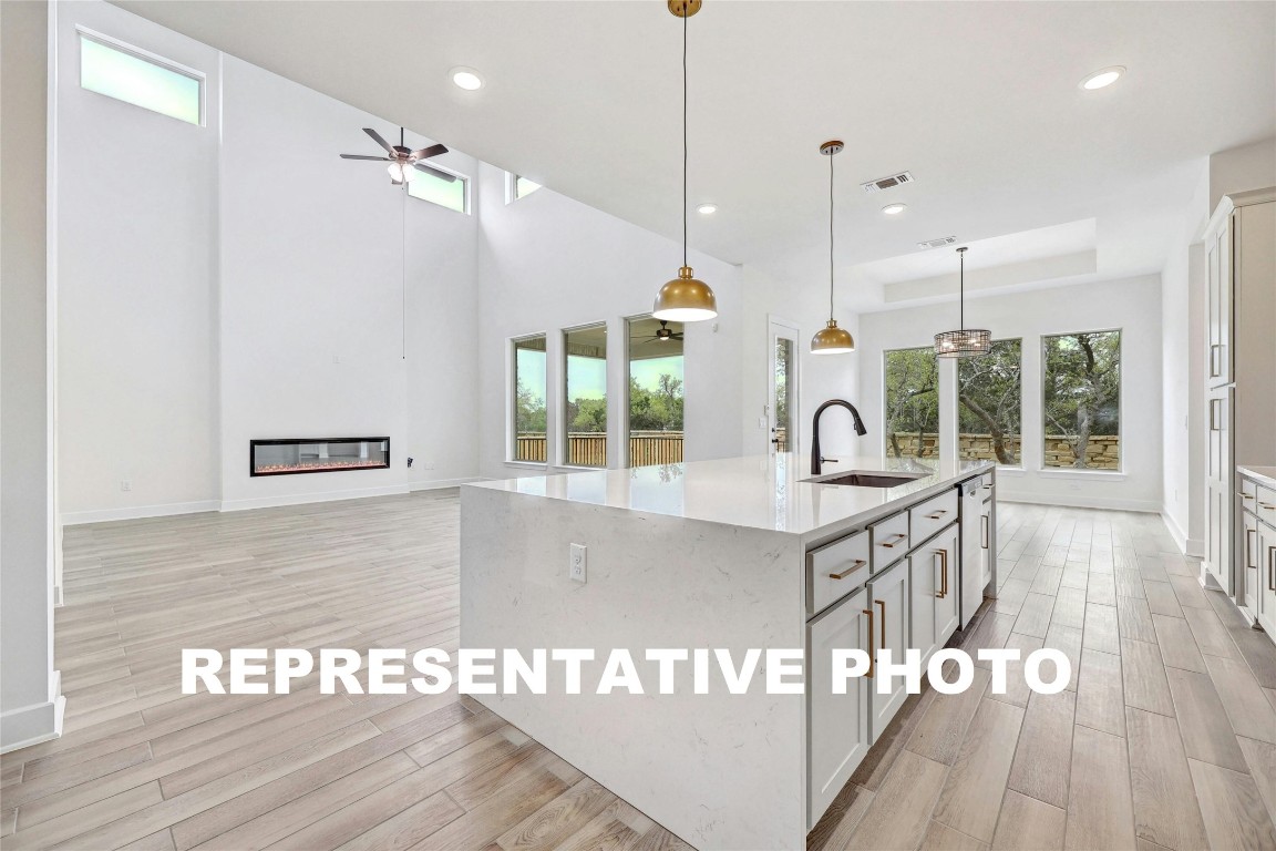 a open kitchen with granite countertop a stove a sink a dining table and chairs with wooden floor