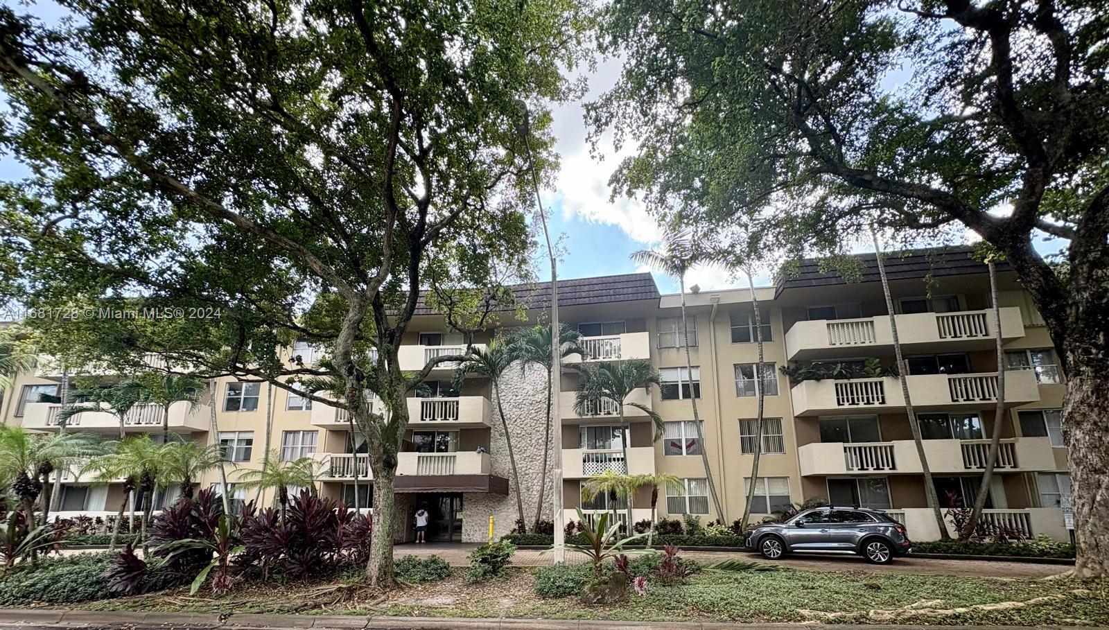 a front view of a building with streets and trees