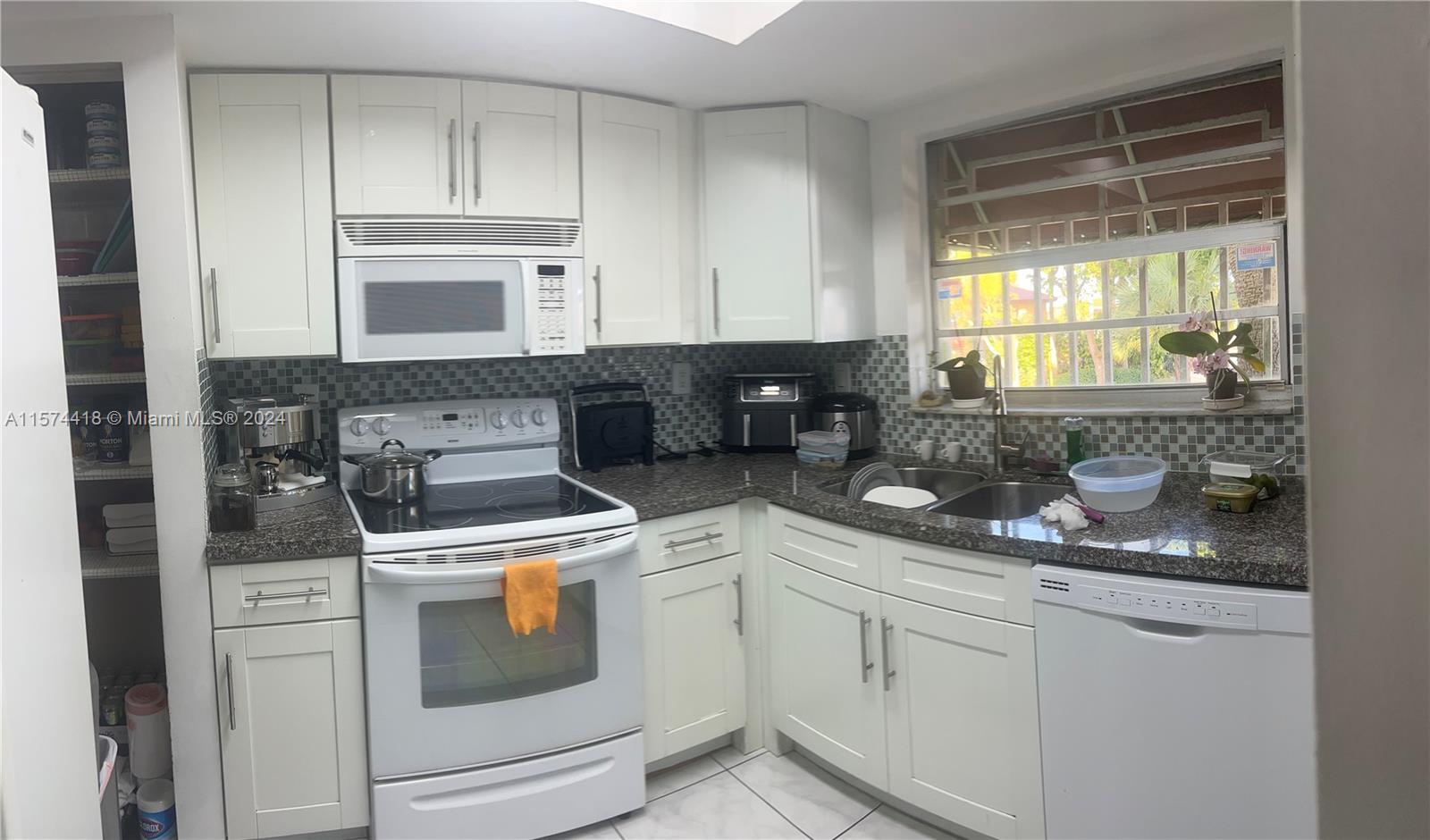 a kitchen with white cabinets and white appliances