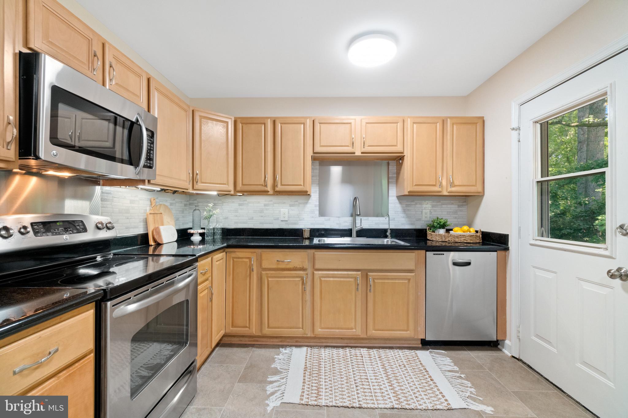 a kitchen with stainless steel appliances granite countertop a stove sink and cabinets