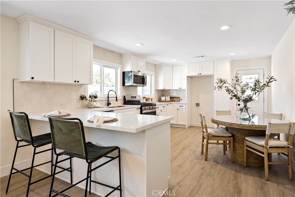 a kitchen with stainless steel appliances kitchen island granite countertop a dining table chairs and a refrigerator