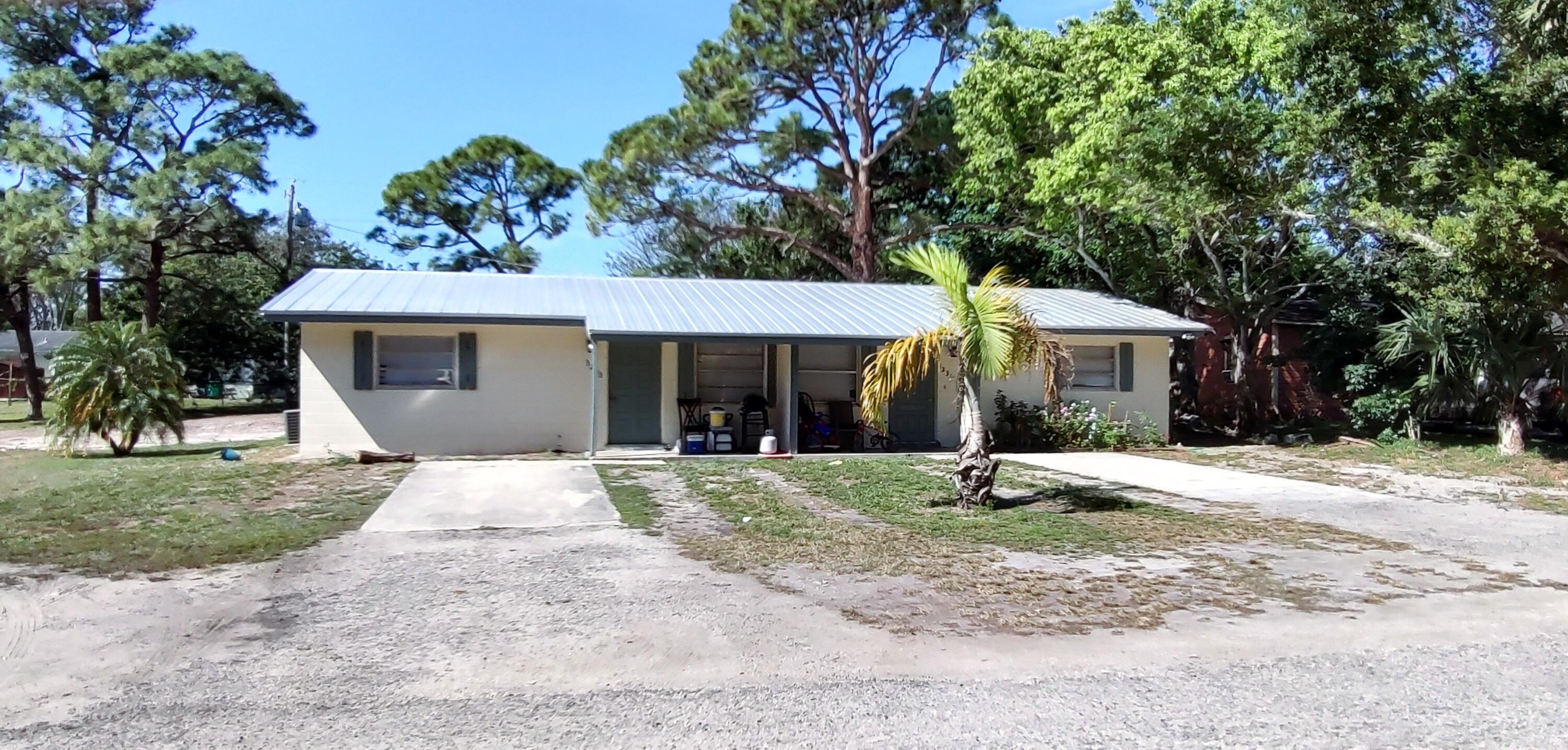 a front view of a house with a yard and potted plants