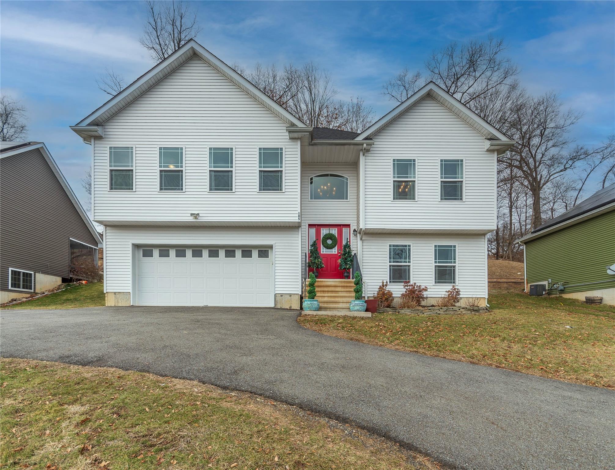 Split foyer home with cooling unit, a front yard, and a garage