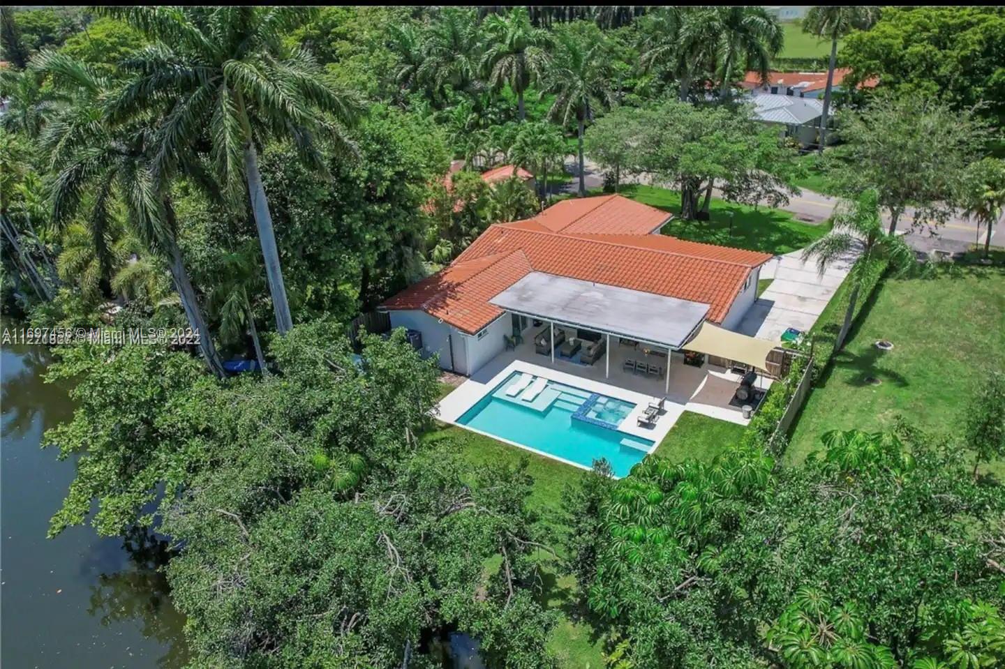 an aerial view of a house with garden space and trees all around