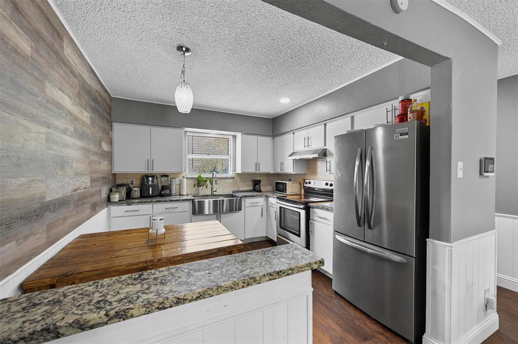 a kitchen with a refrigerator a sink a center island a stove and cabinets