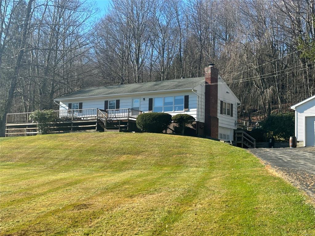 View of front facade with a front yard and a wooden deck