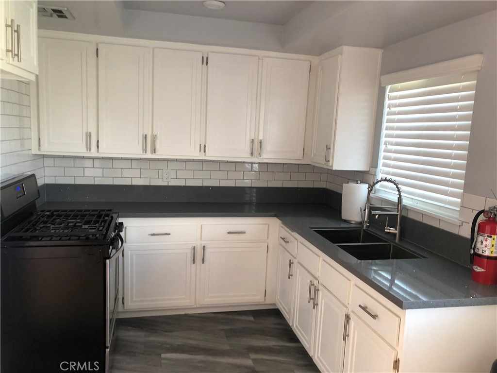 a kitchen with granite countertop white cabinets and black appliances