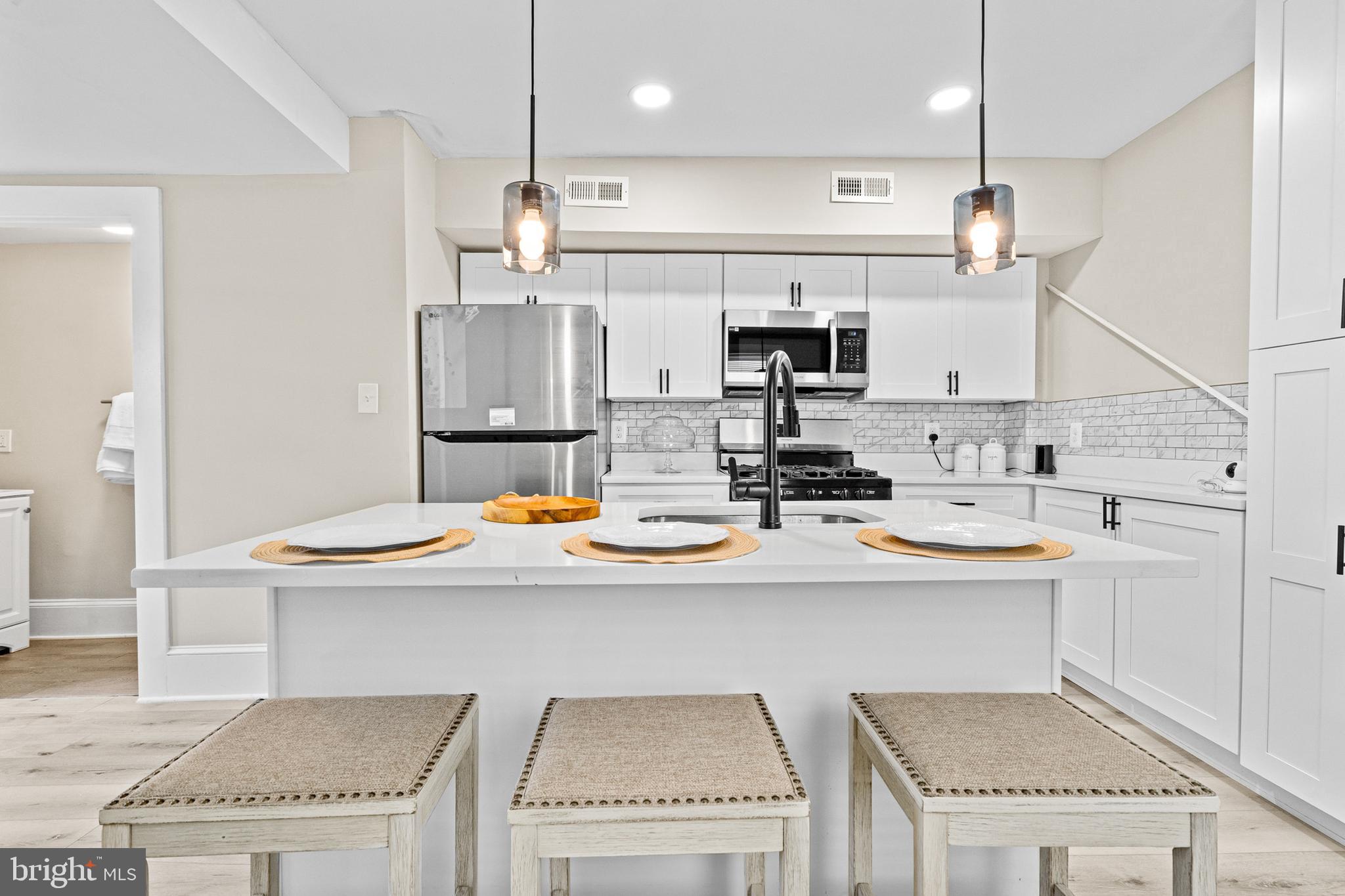 a kitchen with stainless steel appliances kitchen island granite countertop a sink and white cabinets