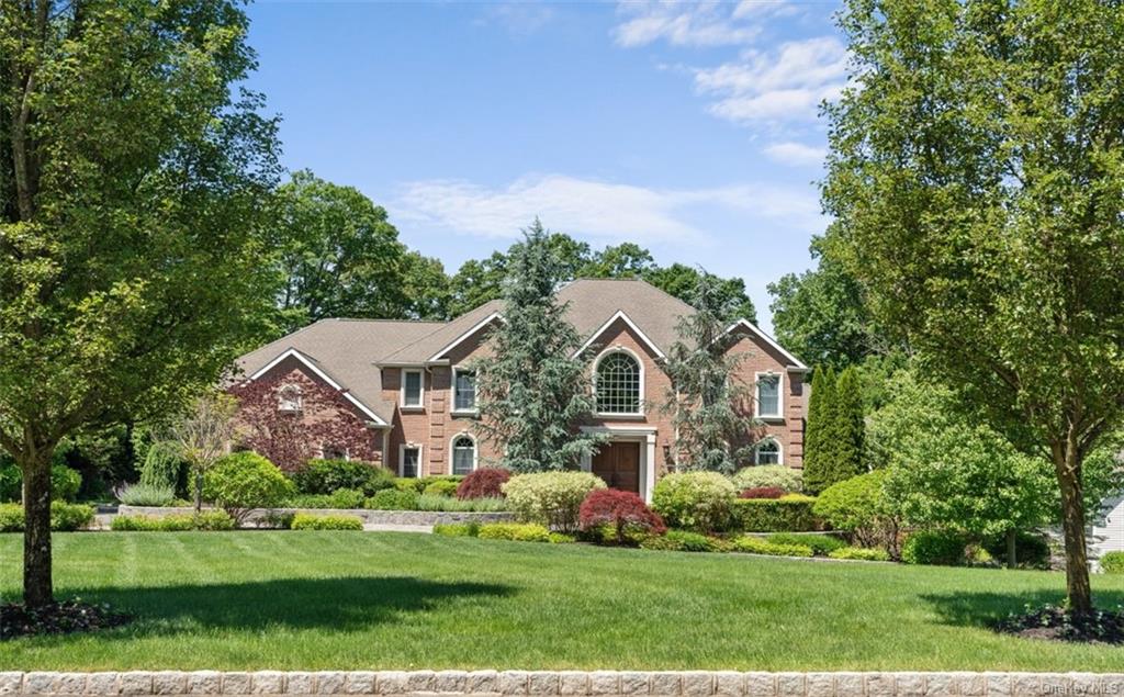 a front view of a house with a garden and trees