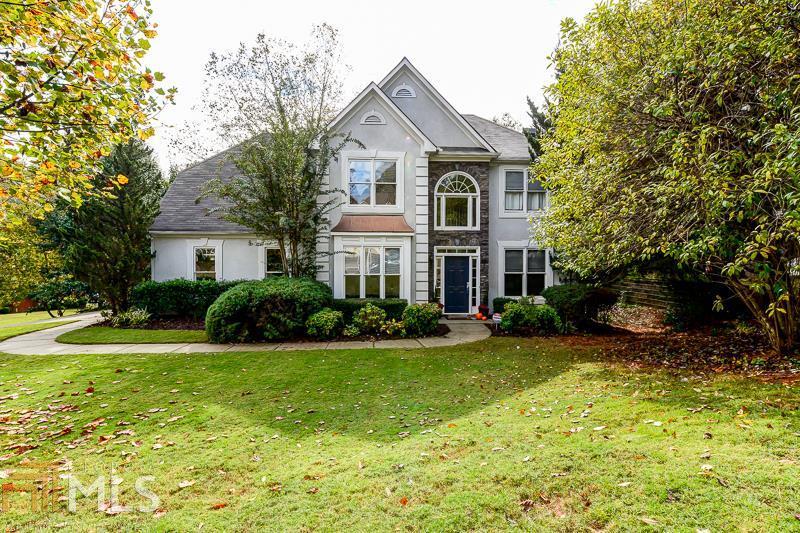 a front view of a house with garden and trees