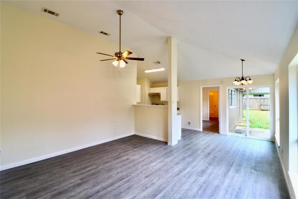 a view of a big room with wooden floor a ceiling fan and windows