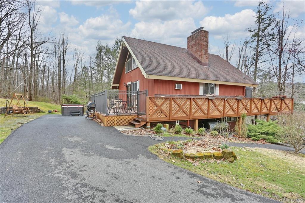 View of front of home with a deck, an outdoor structure, a garage, and a front yard