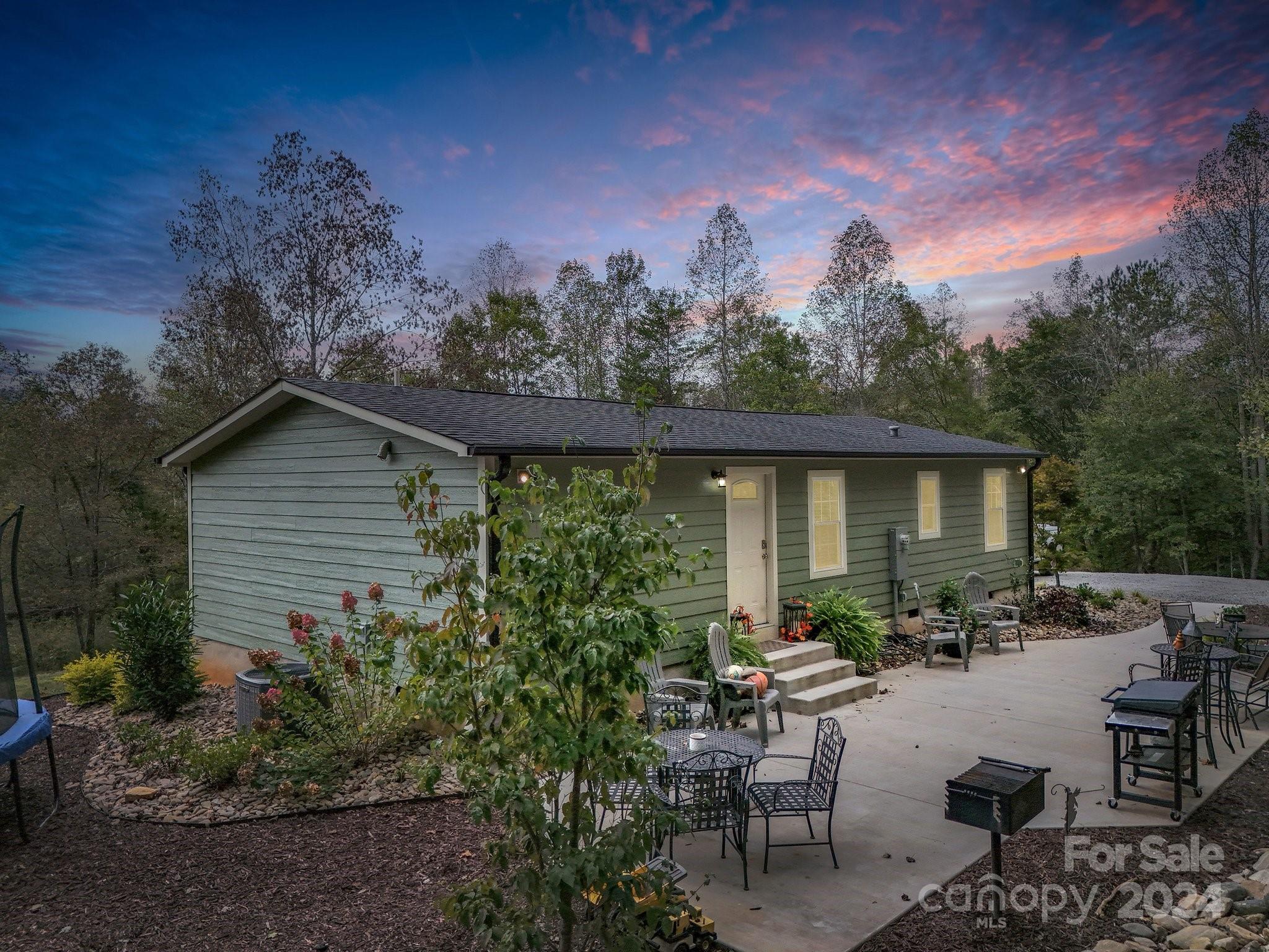 a backyard of a house with large trees and outdoor seating