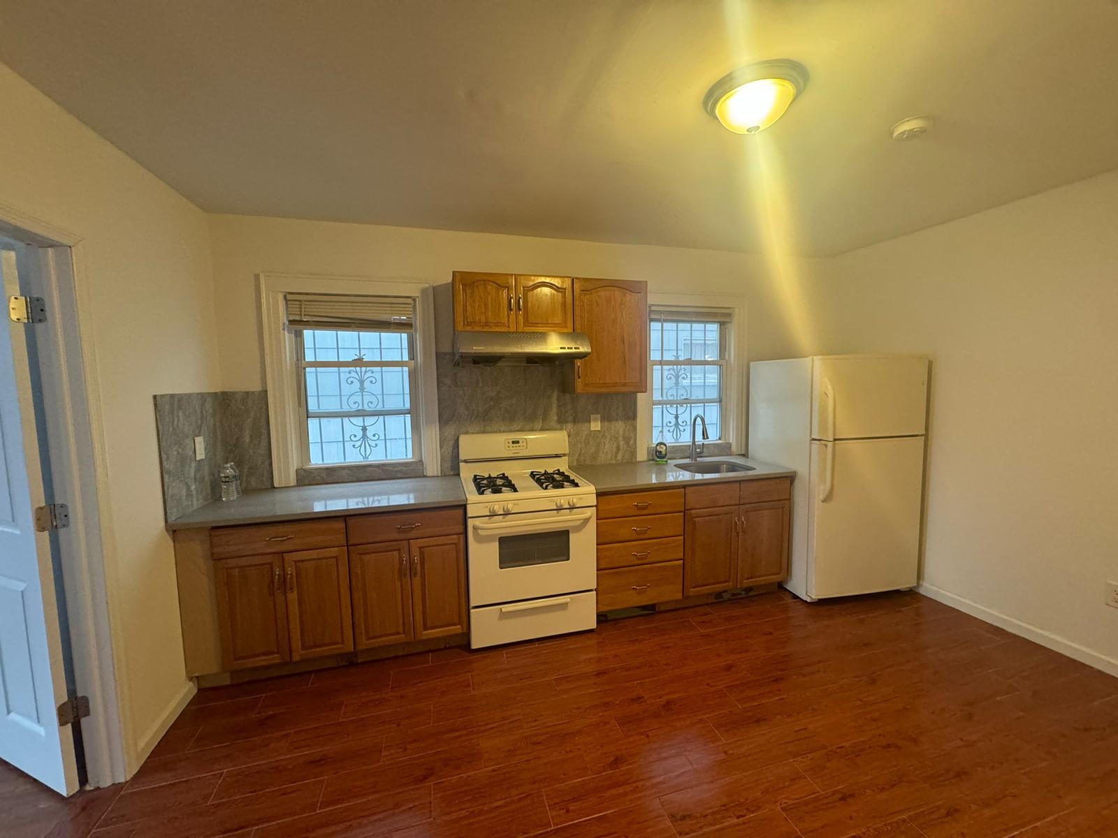 Kitchen featuring white appliances, plenty of natural light, dark wood-type flooring, and sink