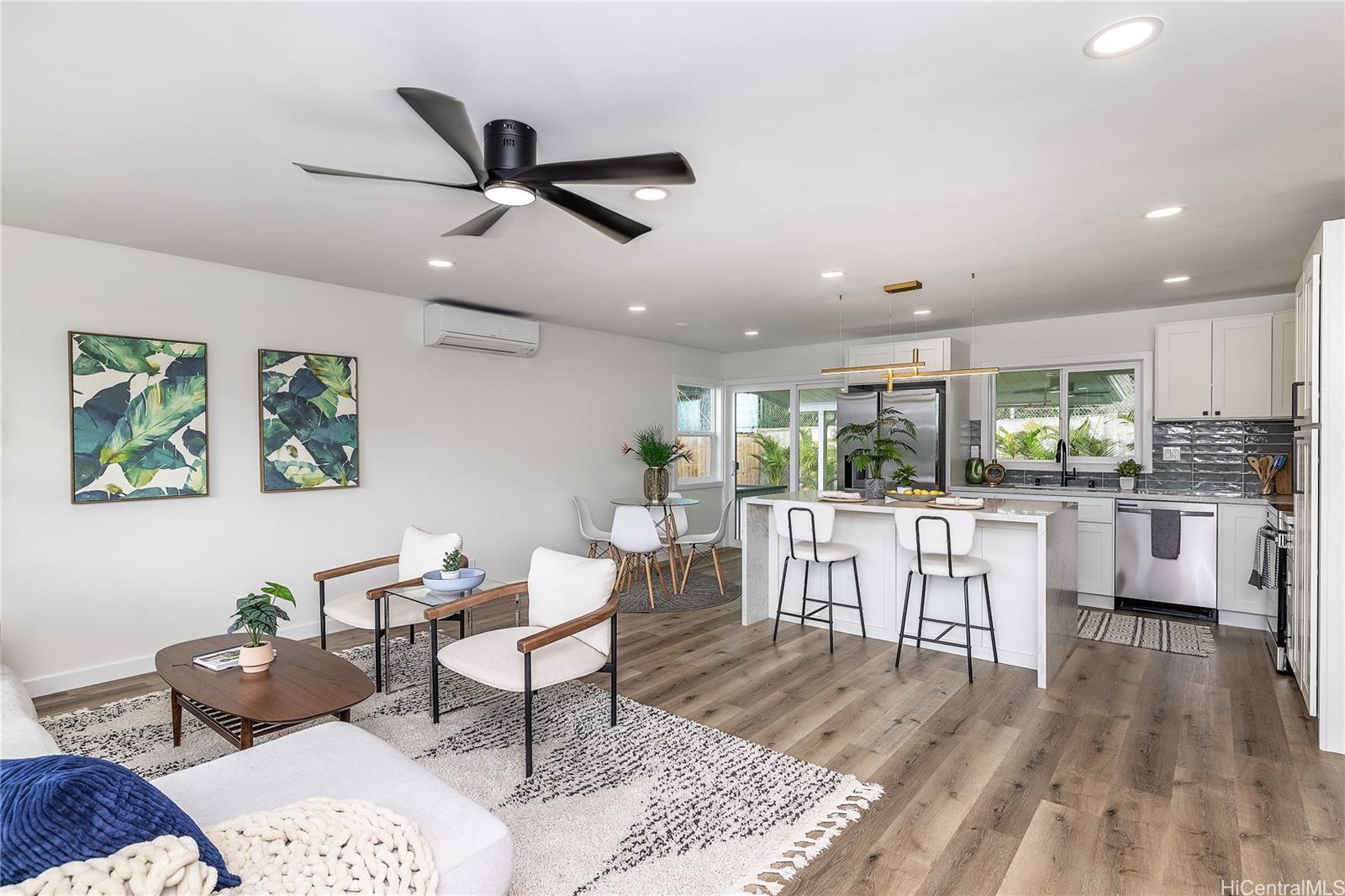 a living room with stainless steel appliances kitchen island granite countertop furniture and a wooden floor