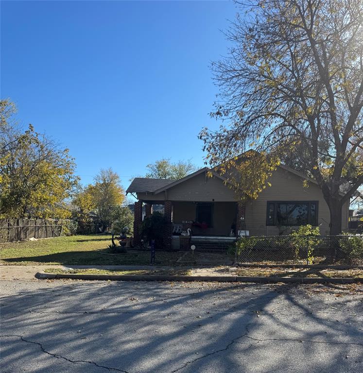 a front view of a house with a yard and a large tree