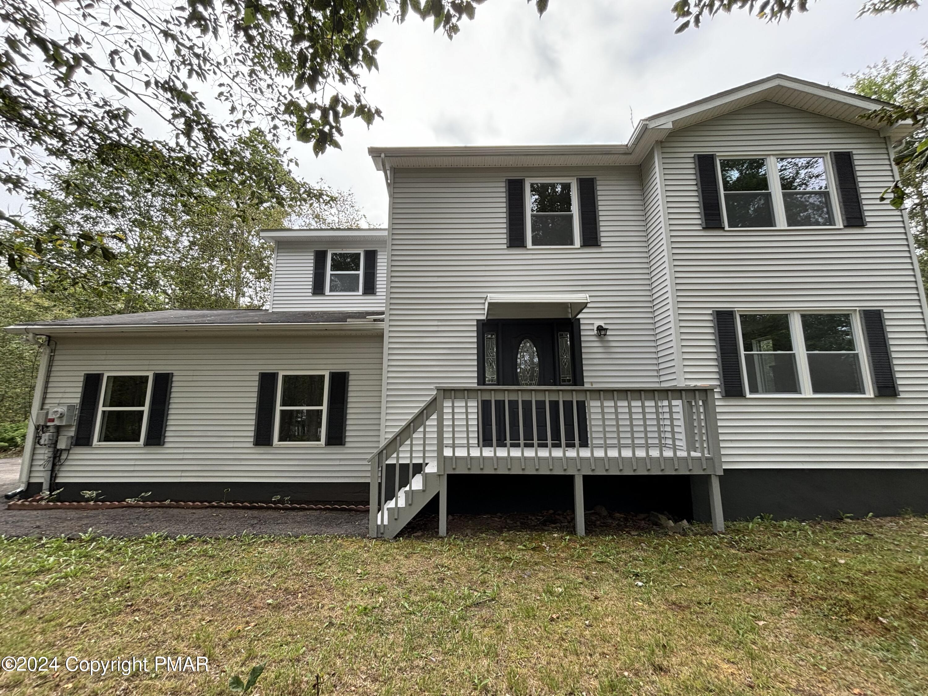 a view of a house with a wooden deck and a yard